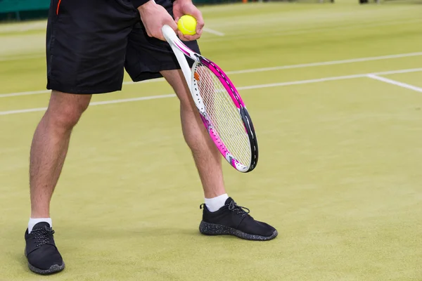 Male player\'s hand with tennis ball getting ready to serve on a