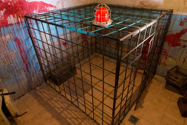 Red lamp on the iron cage in basement with blood splattered wall