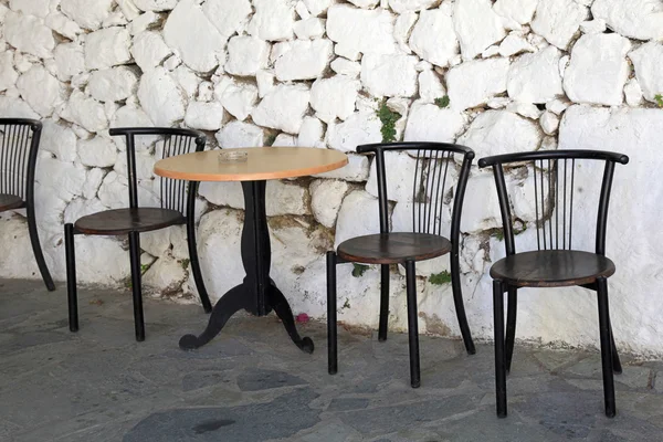 Old chairs and white stone antique wall in greek village