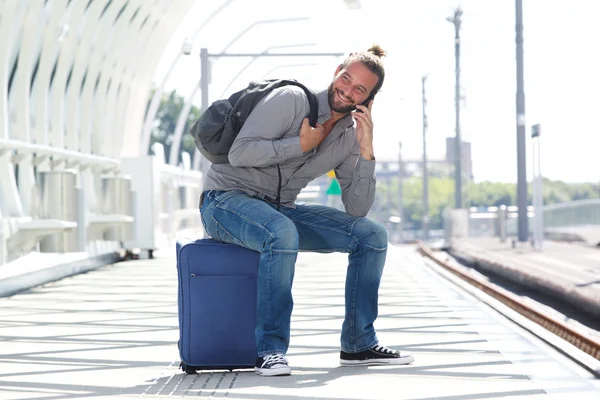Smiling man sitting on suitcase