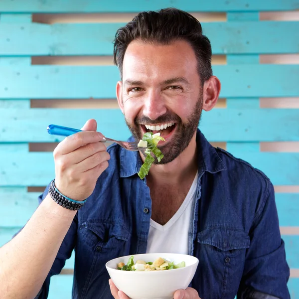 Portrait of cheerful man eating salad