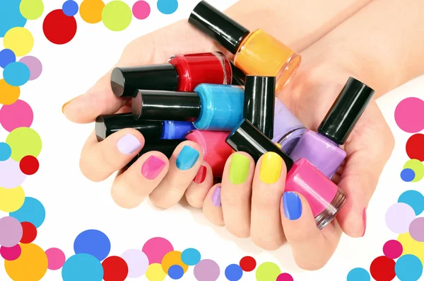 Close up on beautiful woman hands holding many bottles of nail polish and with sexy rainbow manicure.Nail art isolated on white.