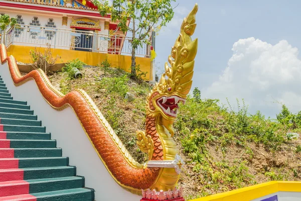 Phuket, Thailand - April 25, 2016 : Yellow Naka (giant snake) statue on top of main stair leading to the replica of Phra That In-Kwaen (Hanging Golden Rock) at Sirey temple, Phuket, Thailand.