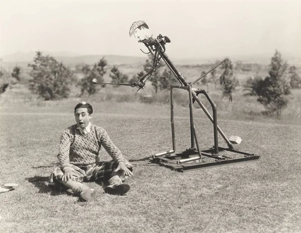 Robot hitting golf ball on man's head