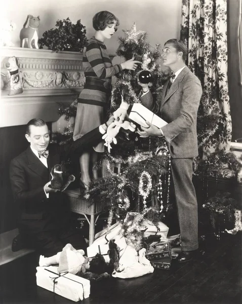 Men helping woman in decorating Christmas tree