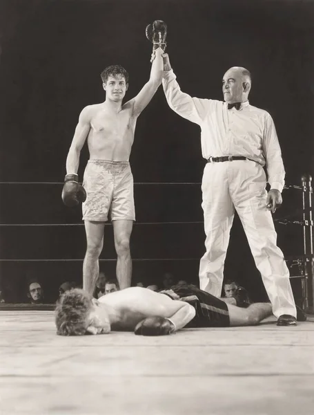 Referee raising hand of winning boxer