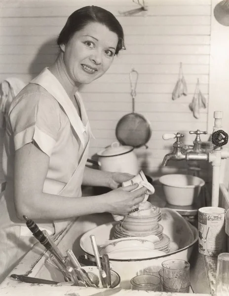 Maid wiping cup in kitchen