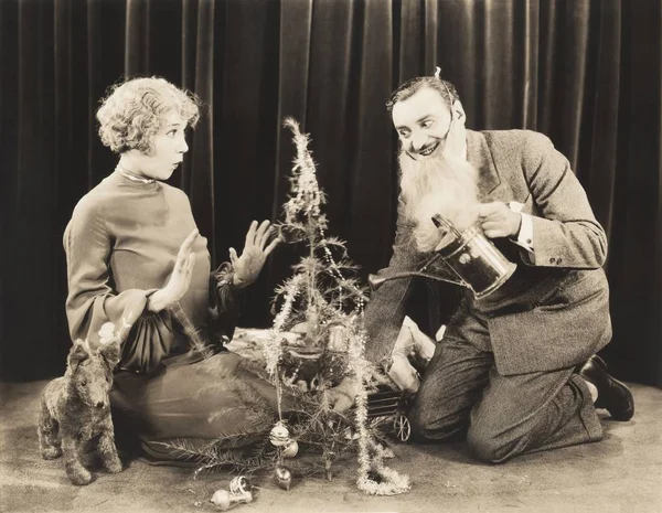 Woman looking at man watering tree