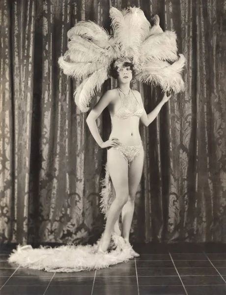 Woman in costume standing against curtain