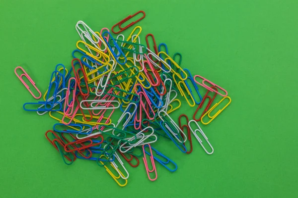 Colored paper clips on a green background