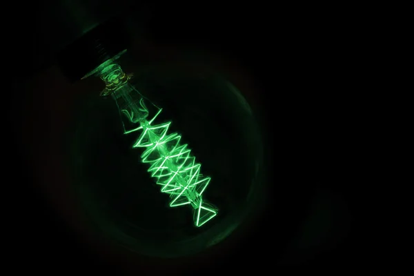 Close up on green light bulb glowing in dark