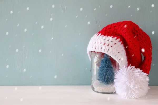 Cute knitted santa hat on mason jar with christmas tree