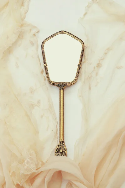 Top view image of vintage hand mirror and lace scarf