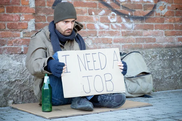 Homeless seated in the street and asking for a job