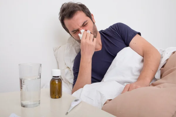 Man feeling bad lying in the bed and blowing his nose