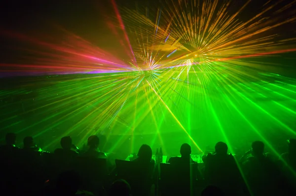 Row of people facing a laser light show