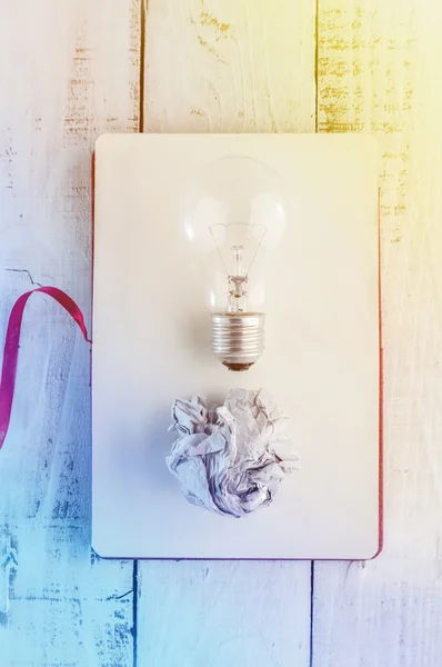 Light bulb with trash paper on blang notebook page