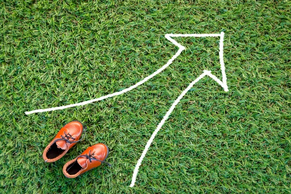 Man shoe with arrow direction drawing on grass