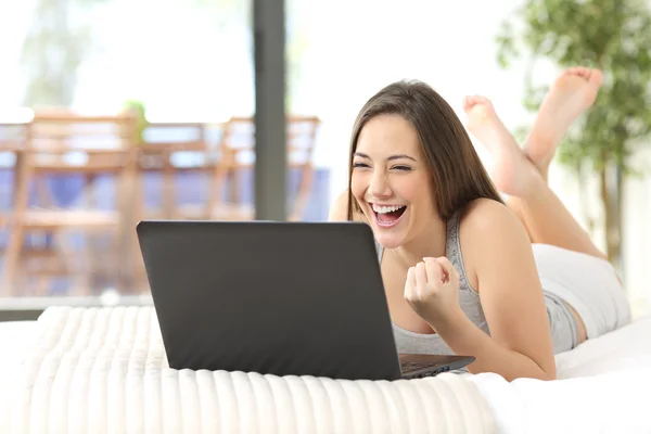 Excited woman winning online watching laptop