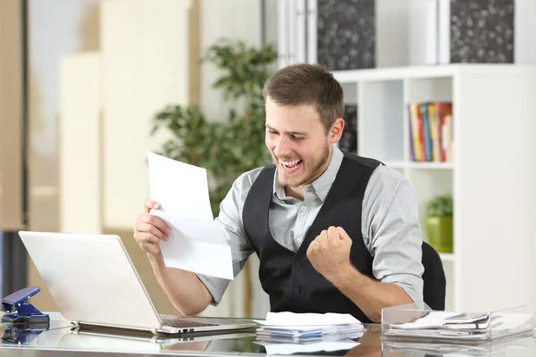 Excited businessman reading a letter at office