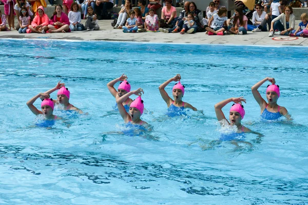 Group of girls in a pool practicing synchronized swimming