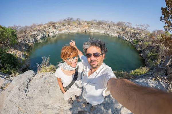 Couple with outstretched arms taking selfie at Otjikoto Lake, one of the only two permanent natural lake in Namibia, Africa. Concept of adventure and traveling people. Fish eye view.
