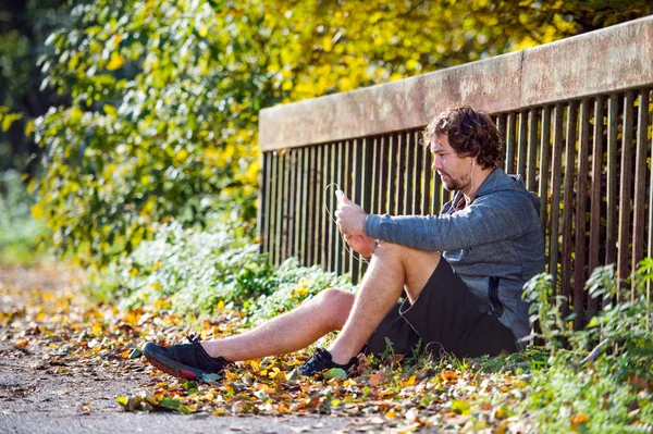 Young runner resting with smartphone