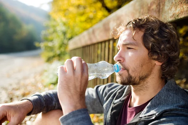 Young man runner drinking water