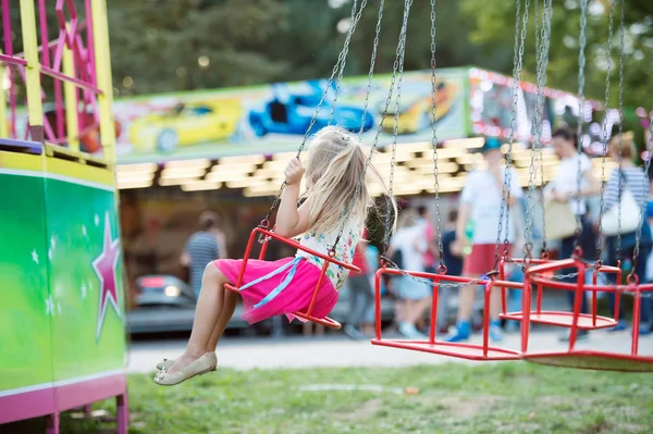 Cute little girl at fun fair, chain swing ride
