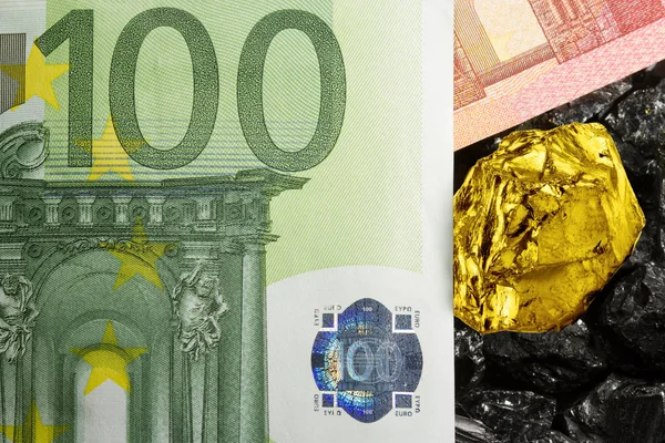 Gold nugget on euro banknotes and raw coal