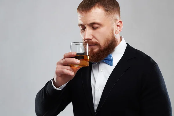 Close up of a stylish handsome bearded man enjoying a brandy or whiskey