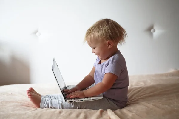 blond toddler playing with pc laptop  at home, indoors.
