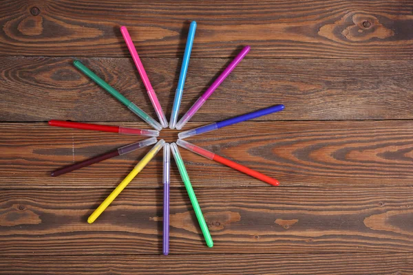 Colored felt-tip pens on a wooden table background, the concept