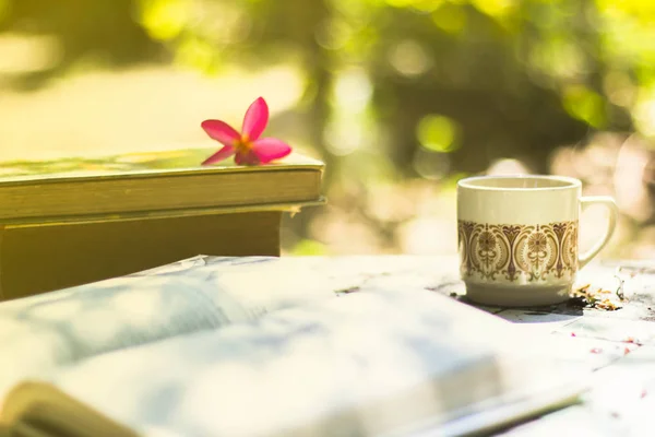 Cup of coffee with flower desk,soft focus background blur book