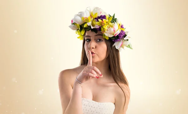 Girl with crown of flowers making silence gesture