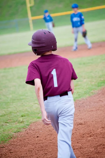 Youth baseball boy on base in maroon jersey