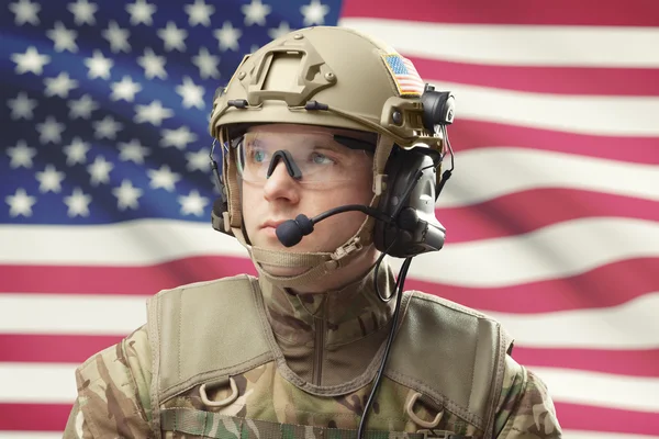 Young military man wearing helmet with USA flag on background - studio shot