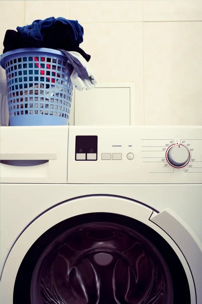 Modern household washing machine and a pile of dirty laundry