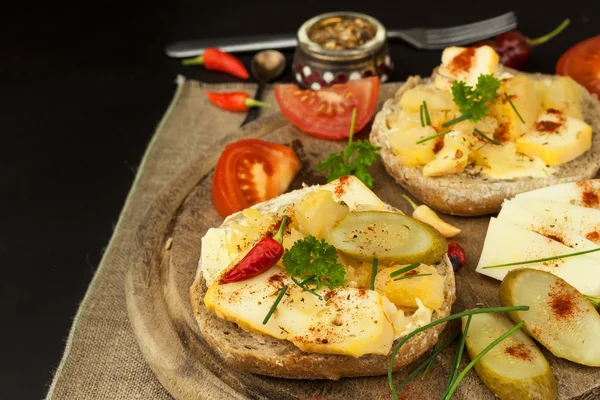 Two kinds of cheese on bread. Healthy breakfast on the kitchen table. Bread with cheese cherry tomato and chilli.