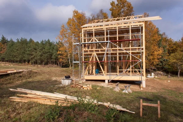 Metal scaffolding around the unfinished house.  Construction of ecological house. Wooden frame of house under construction.Framed New Construction of a House. Timber house in building process