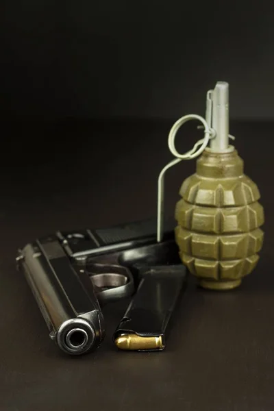 Pistol and a grenade on the table. Preparing for battle. Handgun with ammunition on a dark wooden table. Sales of weapons and ammunition. Advertising on ammunition. New gun and ammunition.