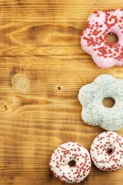 Donuts on wooden background. Sweet donuts with sugar icing. Unhealthy food. The dangers of obesity.