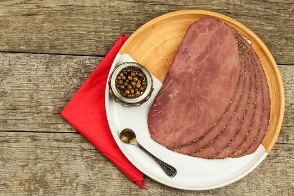 Cold roast beef on a wooden table. Delicacy of beef. Preparing cold refreshments. Traditional meal. Beef roast beef with green pepper.