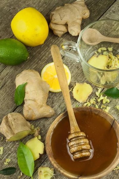 Preparing ginger tea against influenza. Traditional treatment for colds. Ginger, lemon and honey bowl on wooden table. Rustic wooden background. Home Pharmacy.