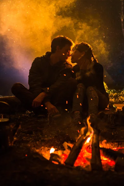 Man plays guitar and woman about the fire on the background of the starry sky