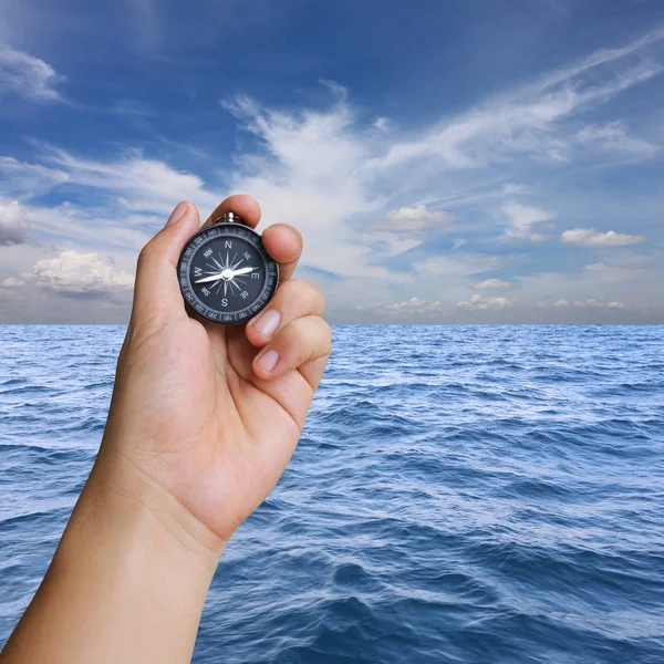 Hand of man holding a compass and view sea.