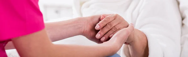 Nurse holding older woman's hand