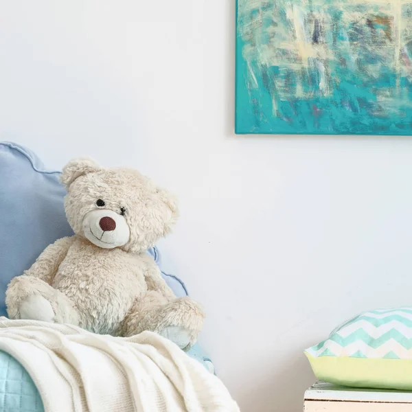Beige teddy bear on a blue bed