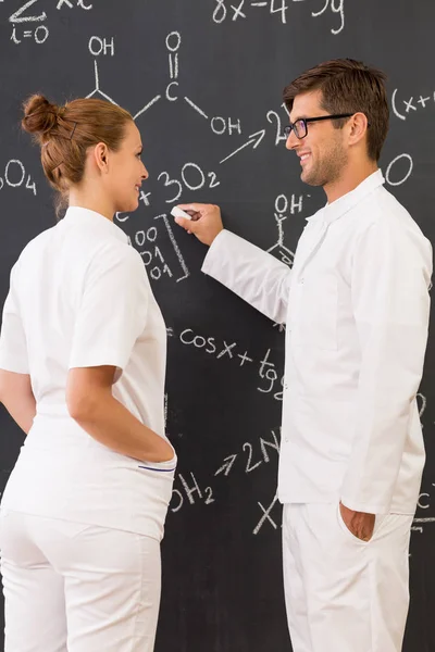 Two scientists standing in front of a blackboard