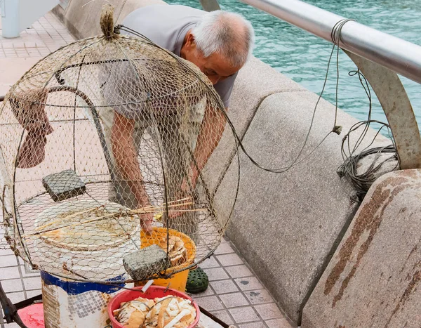 Hong Kong - October 17, 2016: Old Chinese fisherman with his fishing net at the Victoria Harbor of HongKong